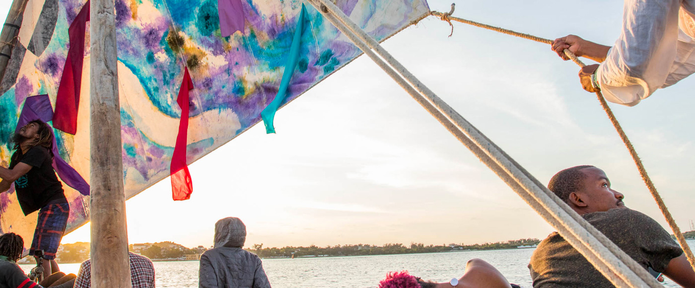 people sailing on a traditional boat with a colorful sail off Shella Beach on Lamu Island in Kenya