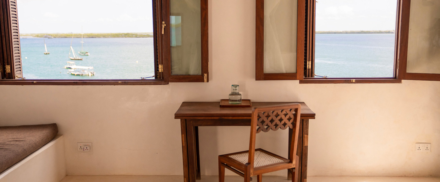 bureau et fenêtre avec vue sur la mer dans une chambre de la villa à Shella Beach sur l’île de Lamu au Kenya