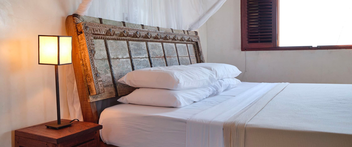 chambre élégante de la villa à Shella Beach sur l’île de Lamu au Kenya avec lit à baldaquin et décoration bois