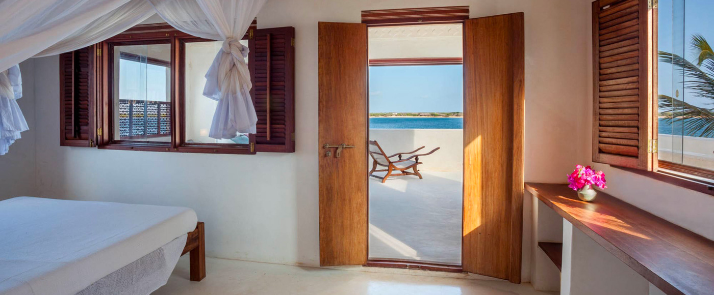 chambre lumineuse de la villa à Shella Beach sur l’île de Lamu au Kenya avec lit à baldaquin et vue sur la mer
