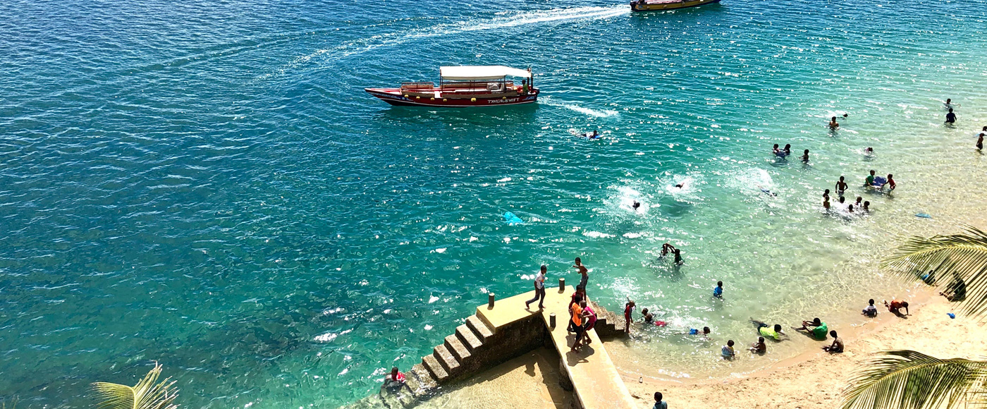 lively beach at Shella Beach on Lamu Island in Kenya with swimming, boats and turquoise water