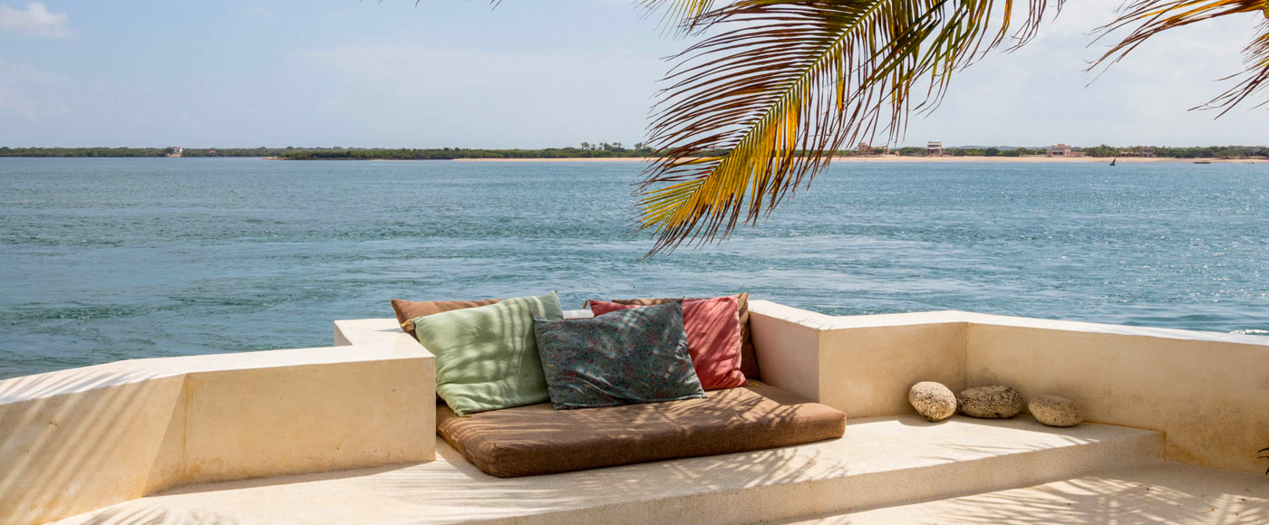 terrace with cushions under palm trees facing the ocean at Shella Beach on Lamu Island in Kenya