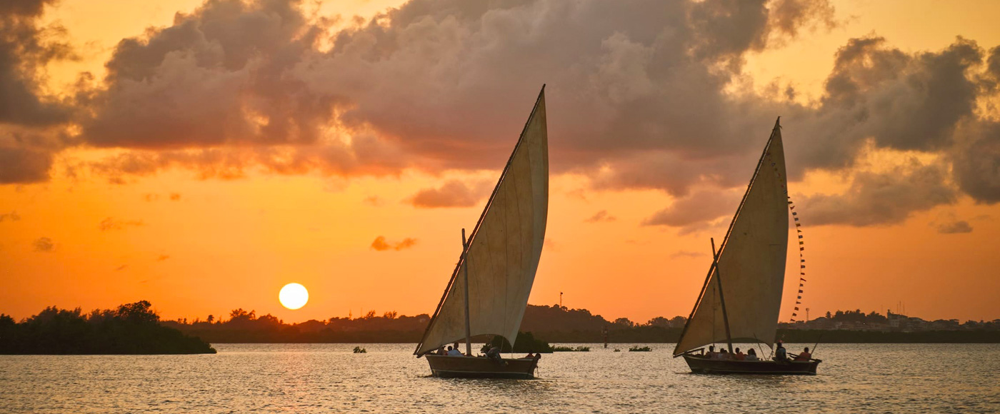 traditional sailboats sailing at sunset near Lamu Island in Kenya