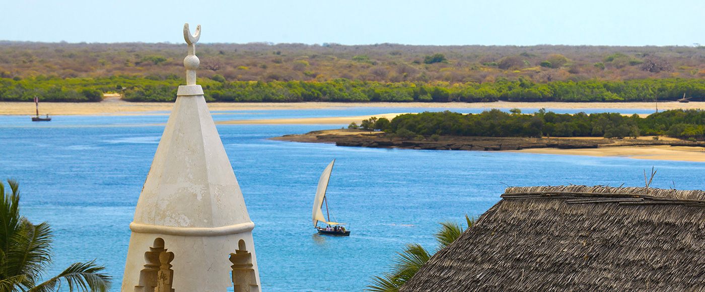 view of Swahili architecture and the ocean around Lamu in Kenya with a dhow offshore